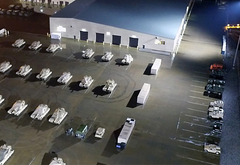 Military base motor pool illuminated by Holophane's Predator industrial LED floodlights at night.